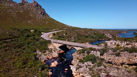 concrete bridge spanning over a river with spectacular mountain views in palmiet, south africa