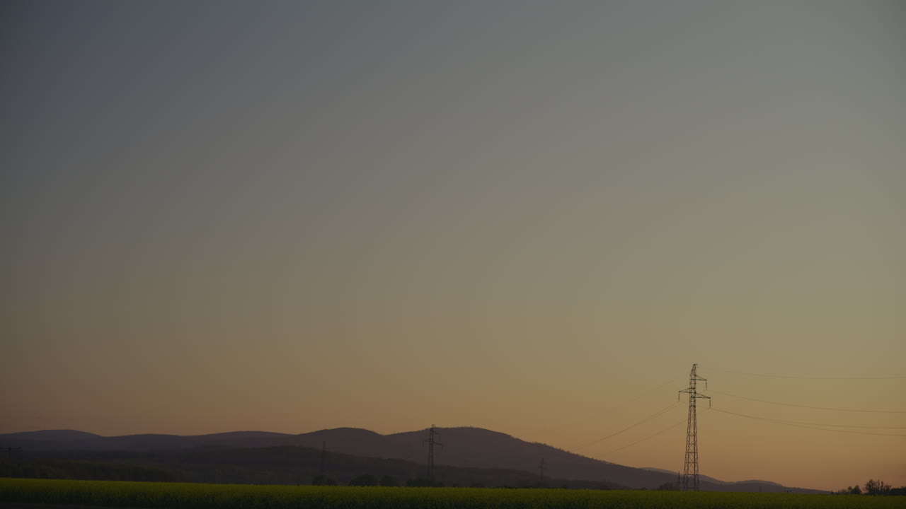 Golden Sunset Over Yellow Rapeseed Field and Mountains
