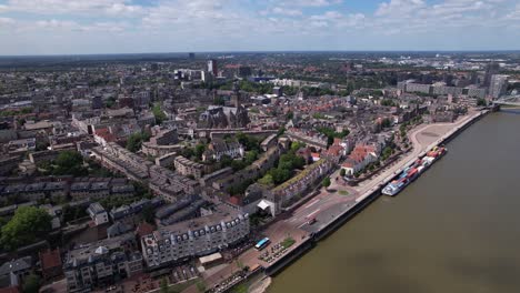 Aerial-sideways-rotating-pan-cityscape-of-Dutch-historic-Hanseatic-city-center-of-Nijmegen-in-The-Netherlands-on-riverbed-of-river-Maas-on-a-sunny-day-partly-in-shadow-of-clouds