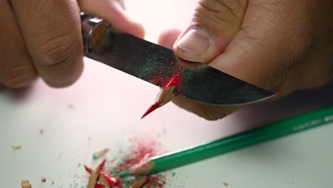 Footage-of-hands-slowly-sharpening-a-pencil-and-some-coloured-pencils-with-a-sharp-knife