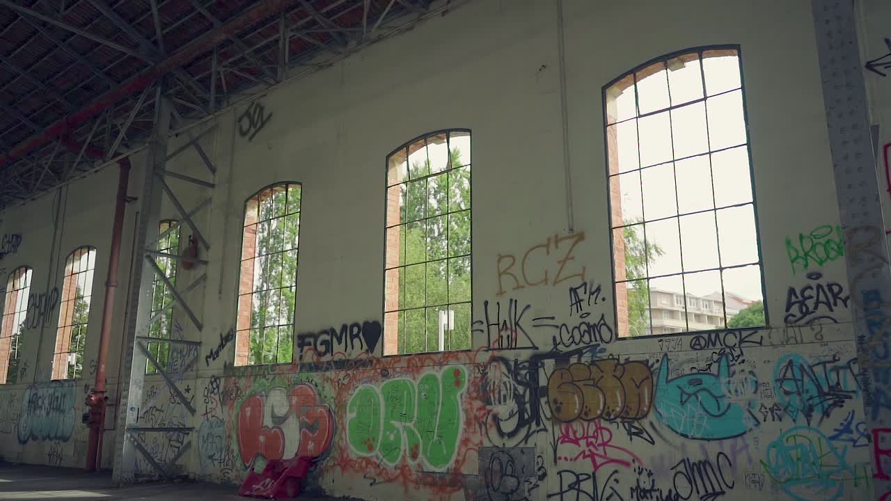 ventanas en nave industrial abandonada con estructura metálica y paredes de ladrillo grafitti.