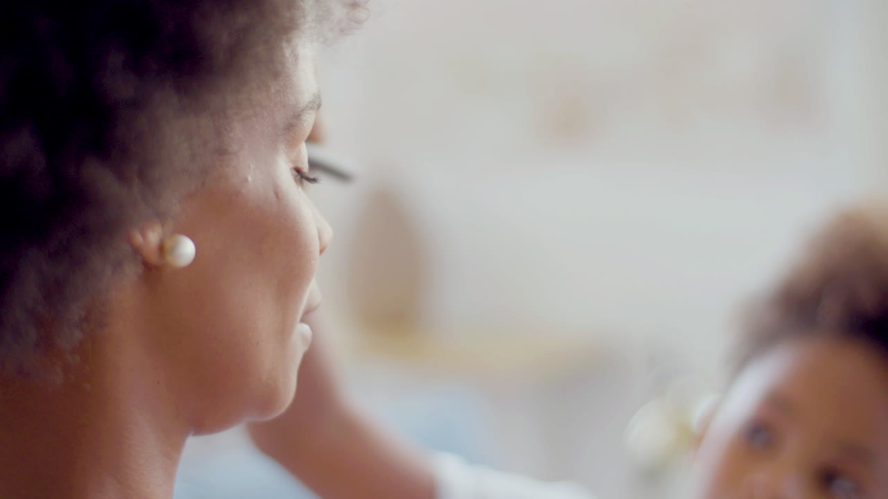 Close up of a Cute Black girl doing make-up on her mother