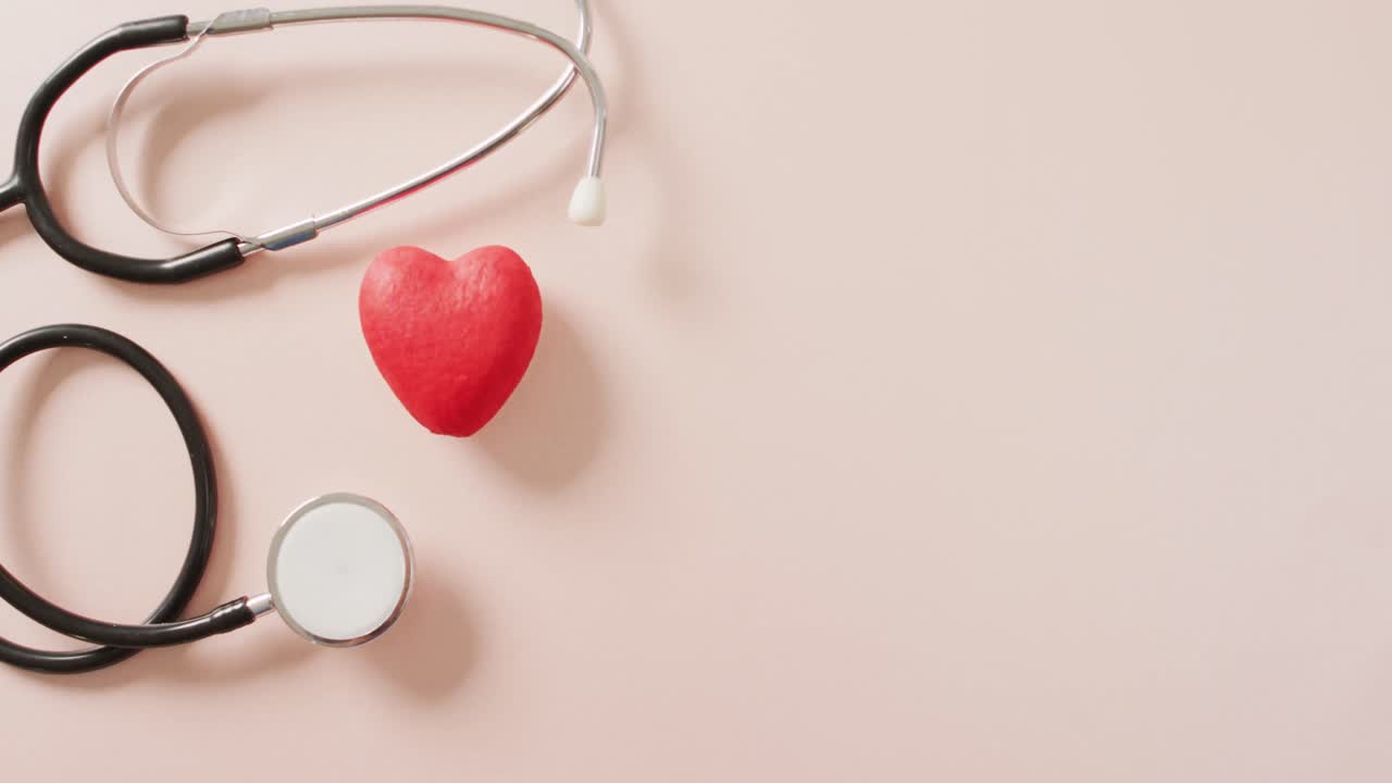 분홍색 배경에 심장이 있는 스테토스코프의 클로즈업 비디오