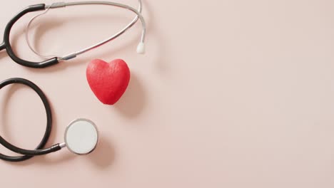 Video-of-close-up-of-stethoscope-with-heart-on-pink-background