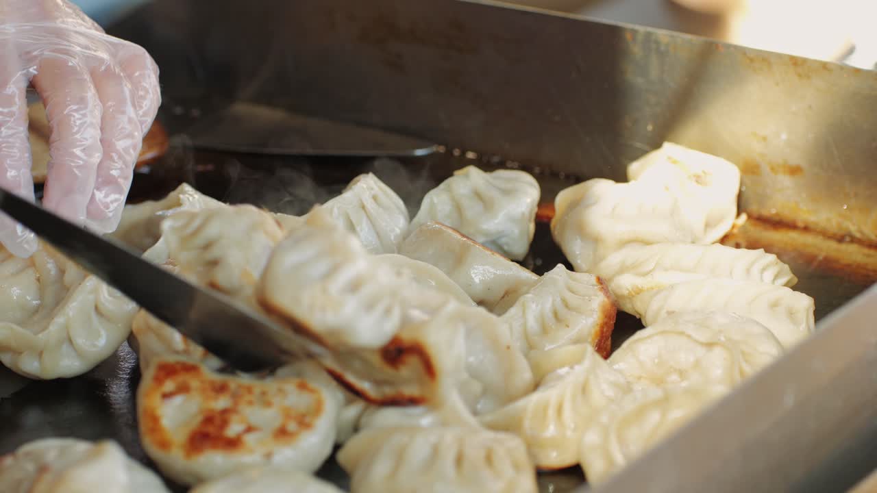 Cooking Chinese and Japanese Jiaozi or gyoza on boiling pan with oil close-up. Dumplings with meat pouring red sweet chilli sauce. Cooking at cafe, restaurant. Asian street food market outdoors.High quality 4k footage