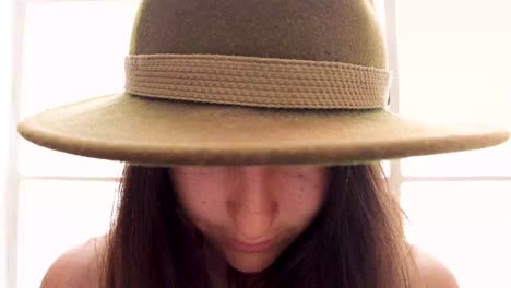 ortrait of attractive woman in hat looking into camera 4k. girl with big eyes peeps out the hat and smiles into the camera