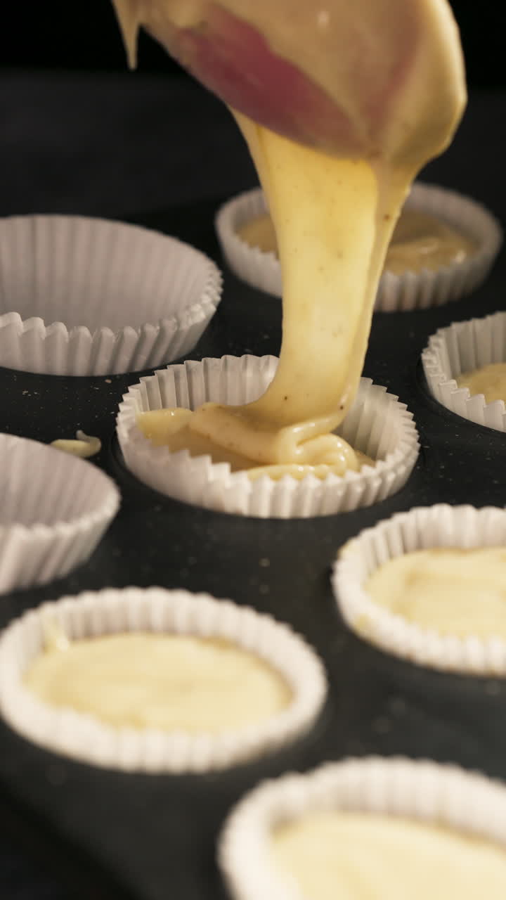 Vista verticale della pastella versata nello stampo per cupcake con i pirottini. Primo piano.