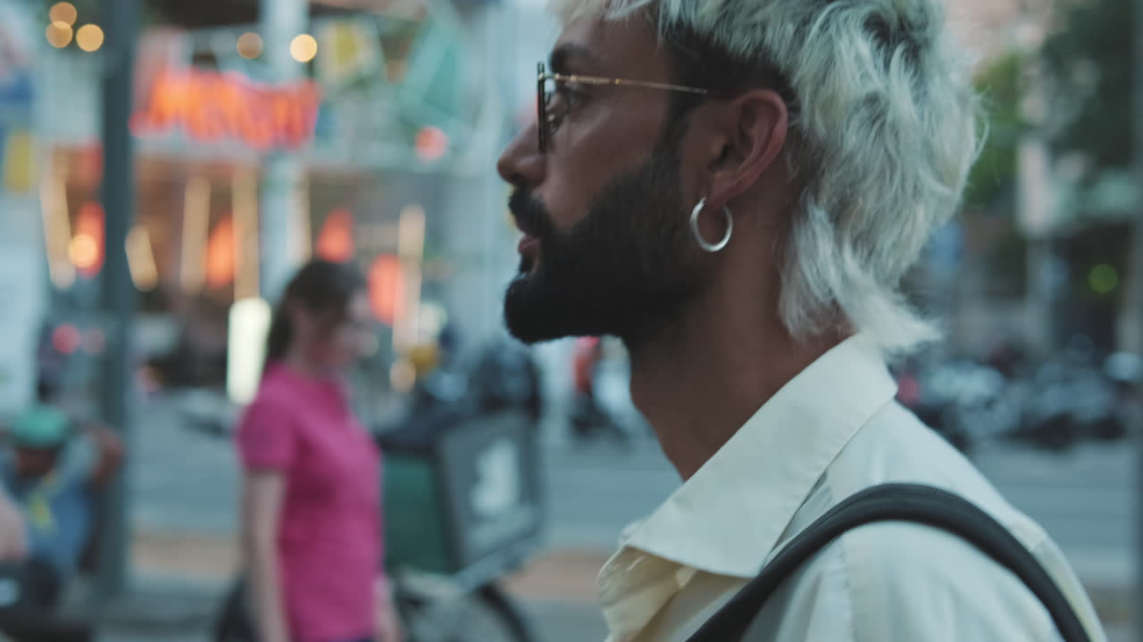 Young Man with Bleached Hair and Glasses Standing on City Street