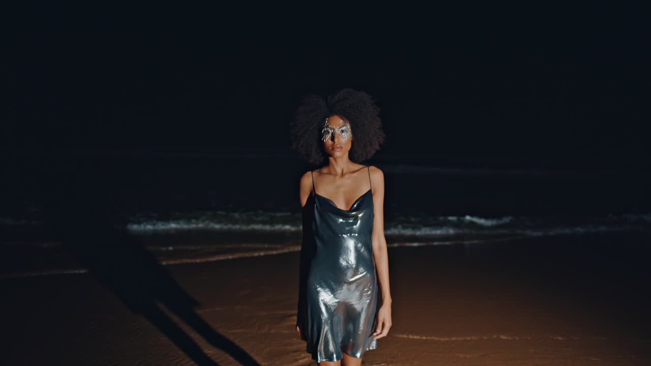 Woman in shimmering dress on a beach at night