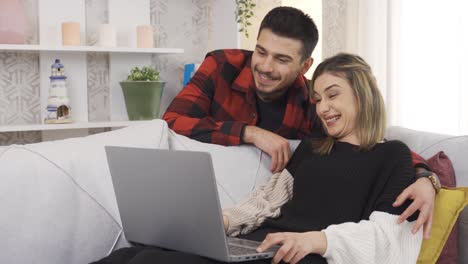 una joven pareja feliz comprando en línea juntos usando una computadora portátil para el comercio electrónico.