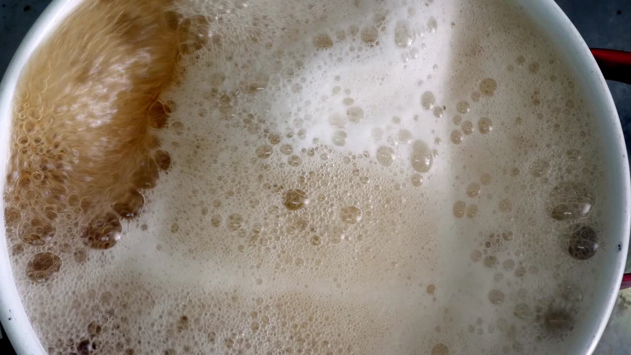 Top shot pan with boiling water and foam in frame - Giant sea snail boiled