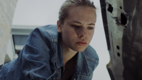 Woman-in-early-20s-checking-under-the-hood-of-a-truck-and-going-under-the-truck-to-find-and-fix-mechanical-problem