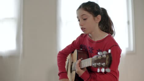 young girl trying to play guitar, having problems