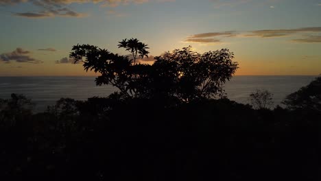 Aerial-drone-forward-movement-capturing-the-mesmerizing-Uvita-Beach-sunset-in-Costa-Rica:-an-enchanting-orange-sun-casting-its-glow-upon-the-sea,-vibrant-natural-beauty