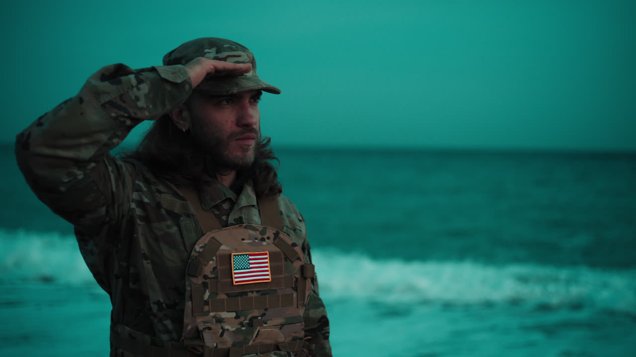 Em uma praia, um soldado americano faz uma saudação militar perto do oceano durante o Dia dos Veteranos
