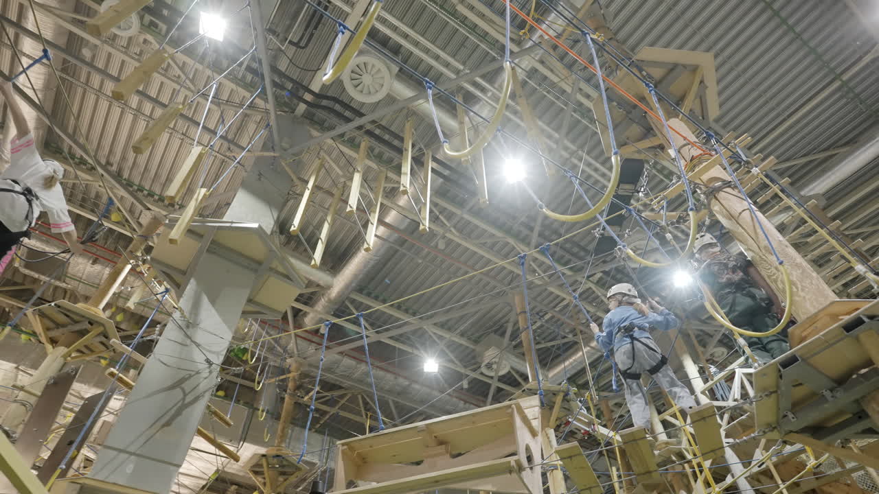 People navigating an indoor rope course