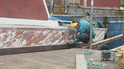 un hombre lijando un casco de barco de madera con tablones de caoba