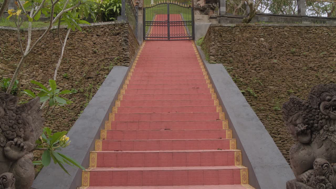 The striking red staircase of Pura Gunung Kawi Sebatu in Bali, Indonesia, surrounded by greenery