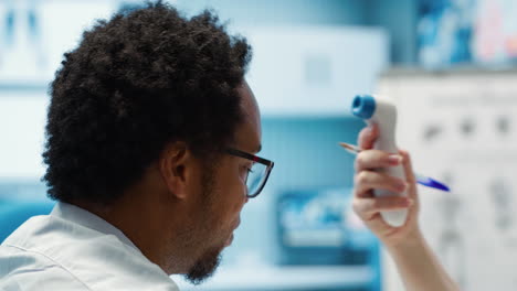 specialist uses a digital thermometer to check for fever and other flu symptoms