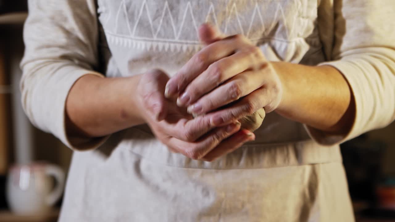 젊은 여인 도자기는 그녀의 손으로 점토 조각을 부드럽게합니다.