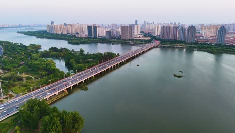 Aerial-dolly-shot-of-vehicles-driving-over-a-bridge-to-reach-downtown-of-Linyi-City,-China