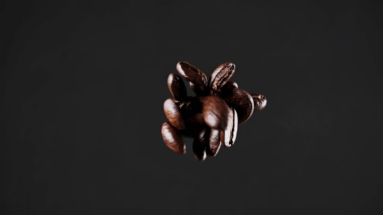 Dynamic video of coffee beans in mid-air against a dark background, captured from a low-angle