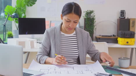 female architect in office at desk working on plans for new building