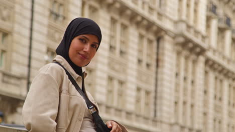 portrait of smiling muslim businesswoman wearing hijab and modern business suit standing outside city office buildings 8