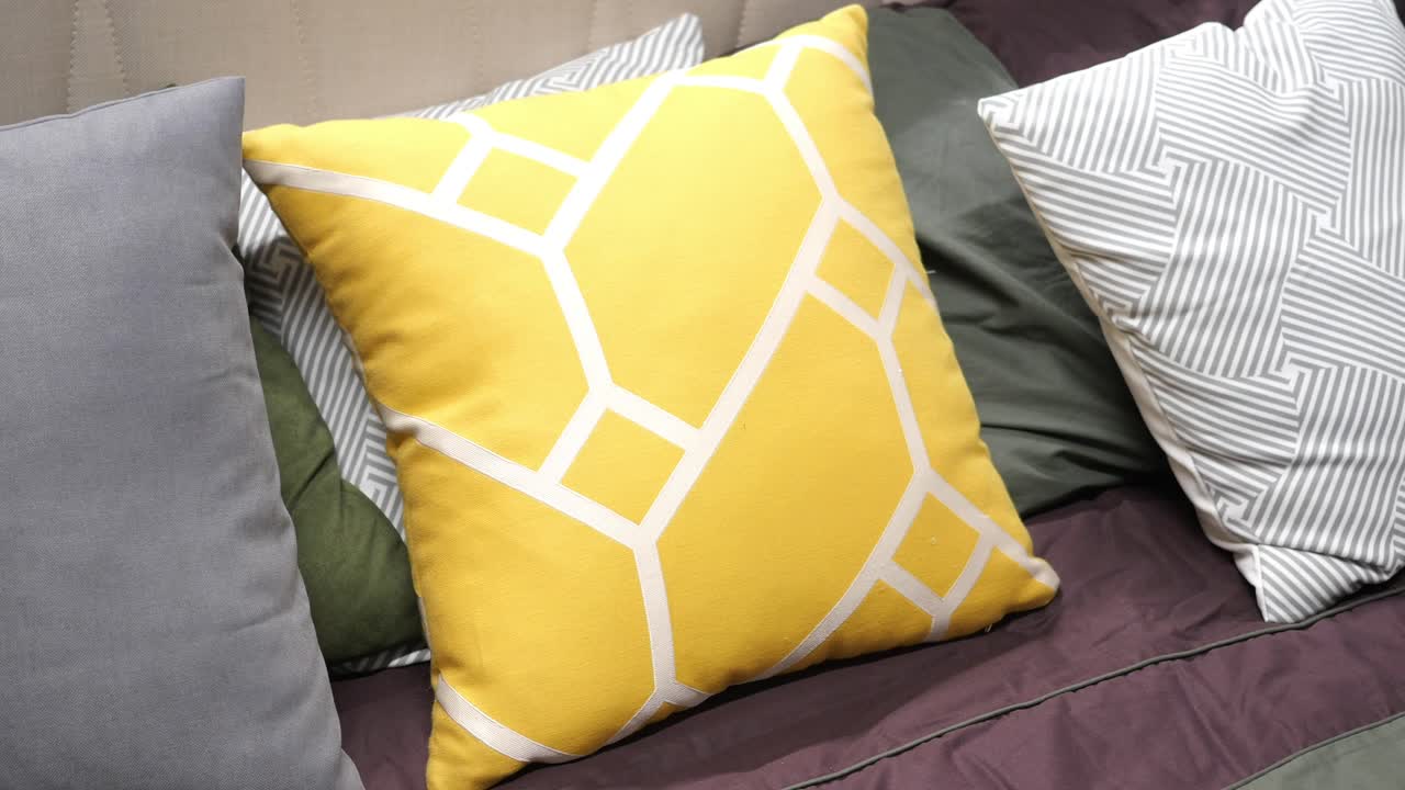 almohada de patrón geométrico amarillo en un sofá con otras almohadas