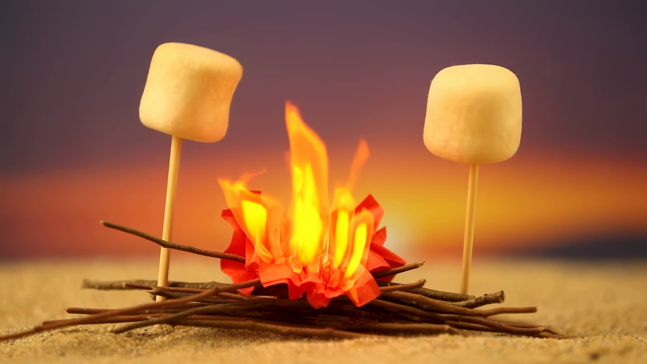 Toasting Marshmallow Over Beach Campfire At Sunset, Closeup Of Two Marshmallows On Skewers Above Flickering