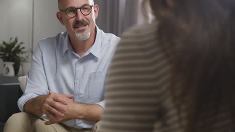 mature man sitting on sofa talking with female counsellor about general or mental health issue 8