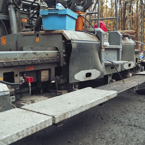 heavy paver machine and workers put the hot asphalt on a street. road construction workers with shovels in protective uniforms.