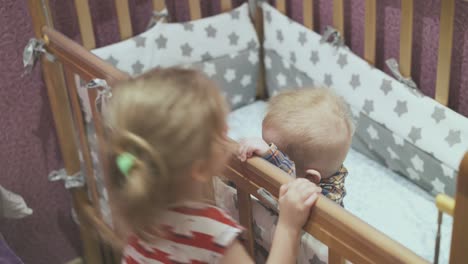 Mädchen-Mit-Lockigem-Haar-Spielt-Mit-Kleinem-Bruder-Am-Kinderbett-Im-Zimmer