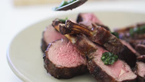 Close-up-of-herb-sauce-being-added-to-rack-of-lamb