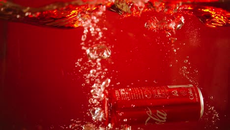 cola can falls into a water tank in slow motion with a red background for use in advertisements