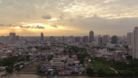 puesta de sol sobre el horizonte de la ciudad de bangkok en el río chao phraya a la derecha