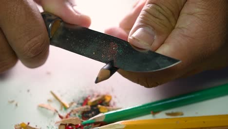 Footage-of-hands-slowly-sharpening-a-pencil-and-some-coloured-pencils-with-a-sharp-knife