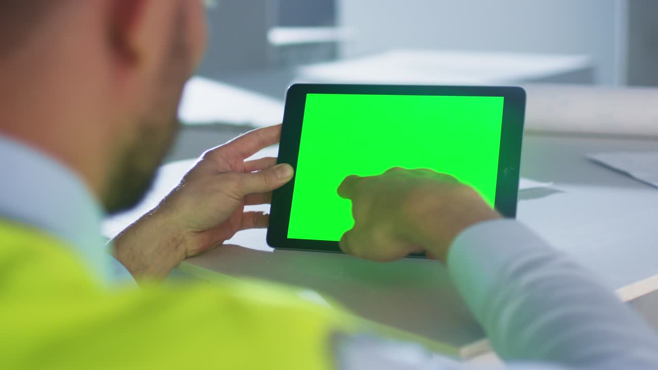 건설 중인 건물 안의 녹색 화면을 가진 태블릿 컴퓨터를 사용하는 엔지니어. 모 사용에 적합합니다.