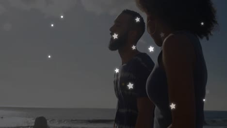 animation of stars over diverse couple at beach