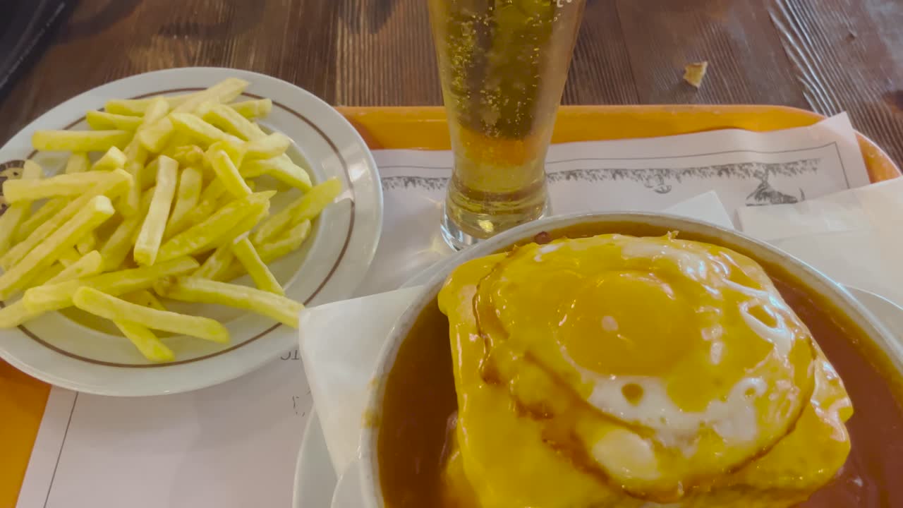 A satisfying meal featuring a glass of beer, crispy fries, and a savory dish topped with a fried egg. Perfect for an easygoing meal and drink pairing, ideal for casual dining and relaxation