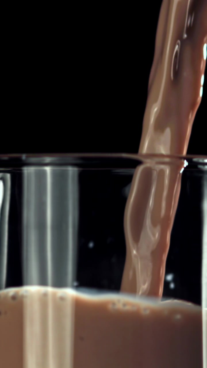 Latte al cioccolato che si versa in un bicchiere al rallentatore