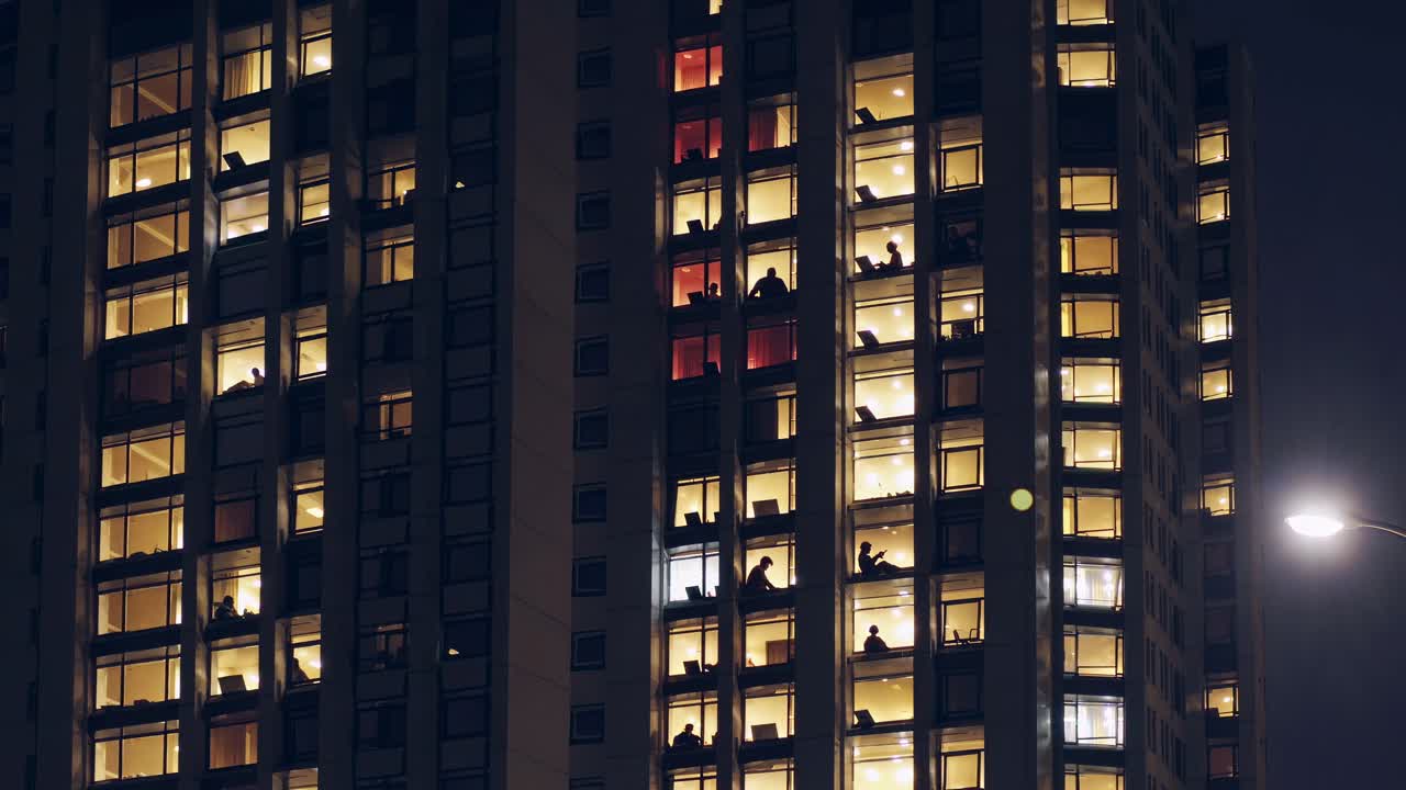 personas que trabajan o estudian en un edificio alto iluminado por la noche