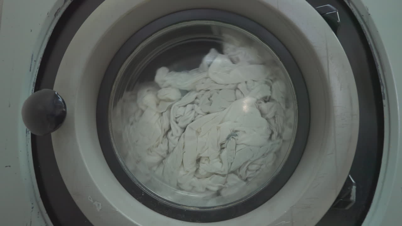 Close up of white bedding spinning in Industrial laundry machine on spin cycle