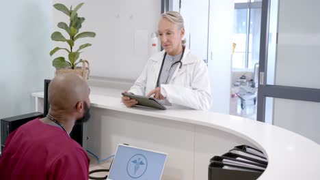 diversos médicos masculinos y femeninos en discusión usando tableta en la recepción del hospital, cámara lenta