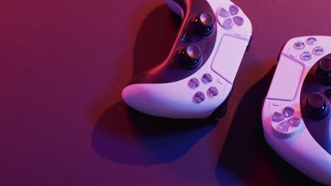 video of close up of video game pad controllers with copy space on neon background