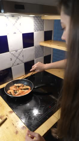 mujer cocinando camarones en la cocina