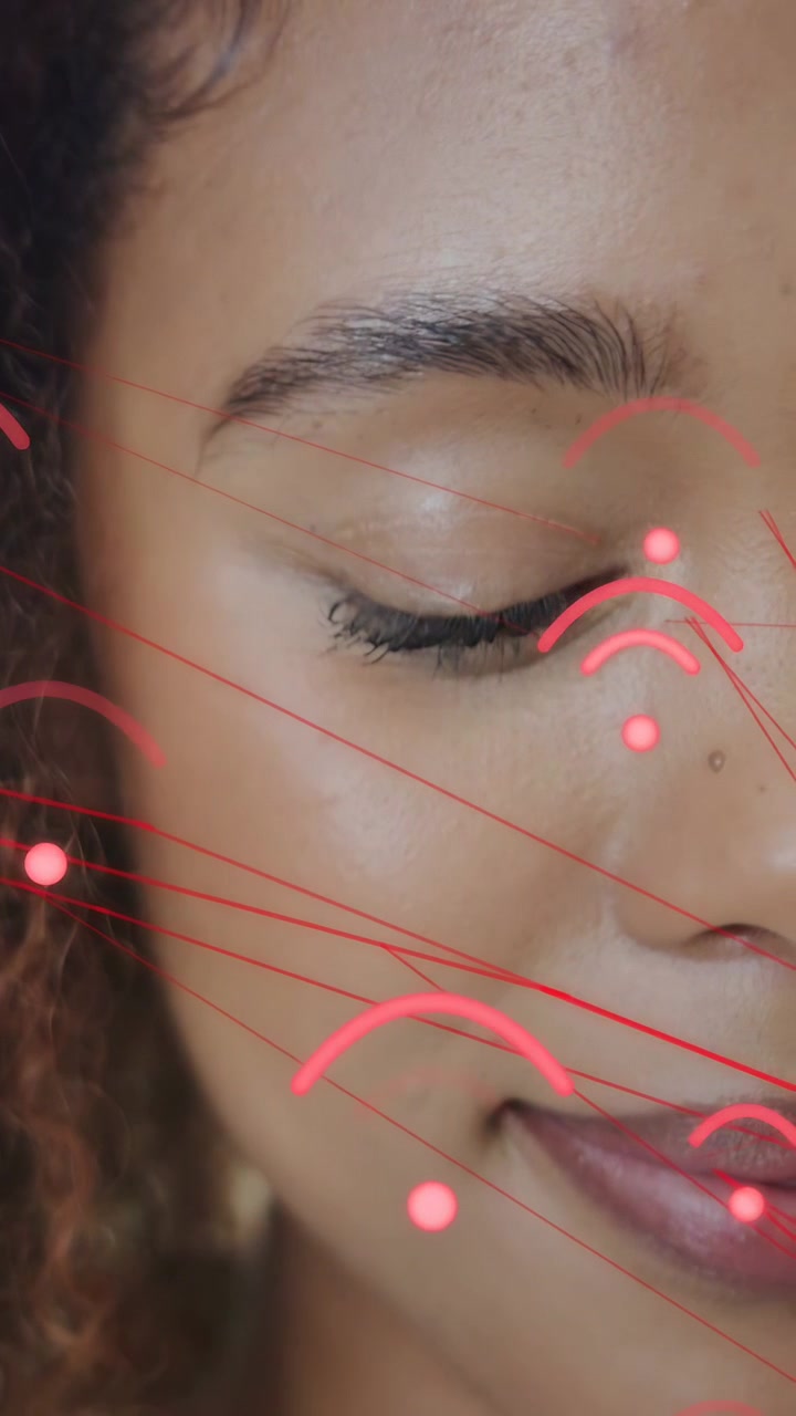 Vertikales Video: AR-Overlay mit rosafarbenen Bögen, die sich am Gesicht ausrichten, lässt eine Frau für Schönheitszwecke blinzeln und lächeln.