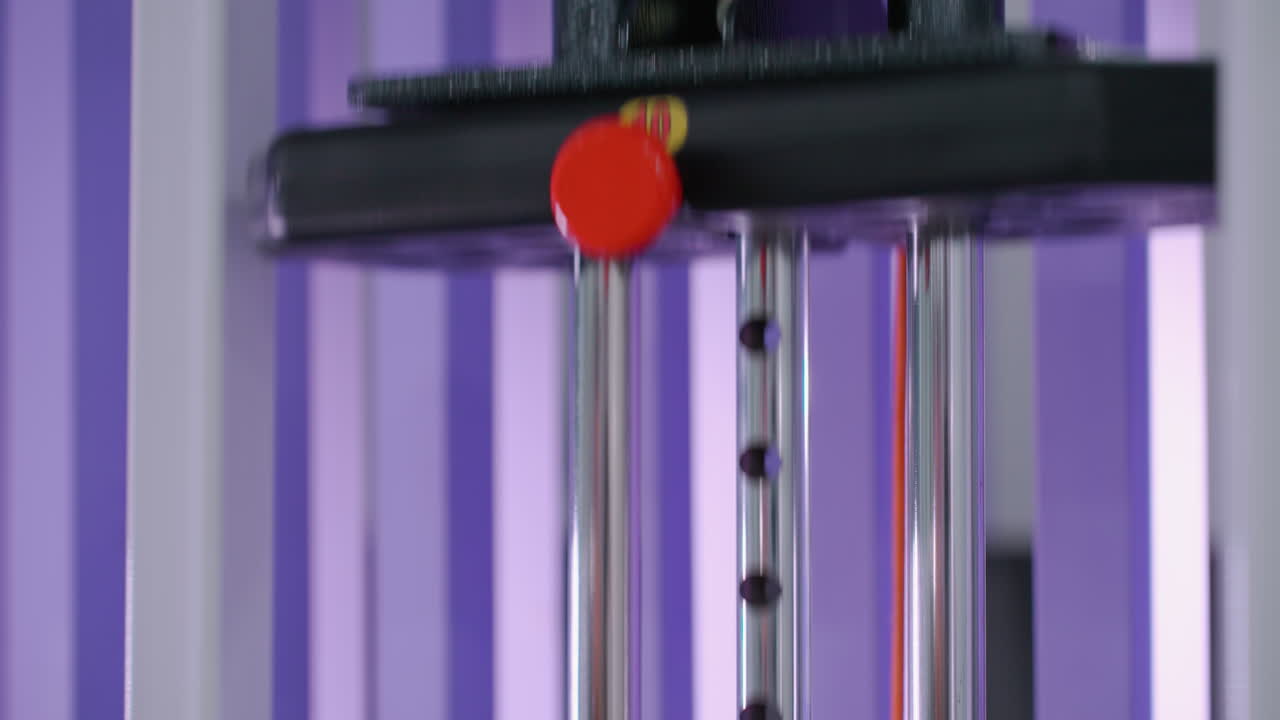 체육관 웨이트 스택이 저항 기계에 내려지는 클로즈업, 통제된 움직임과 힘 훈련을 강조하고, 금속 구성 요소가 활기찬 보라색 배경과 대조됩니다.