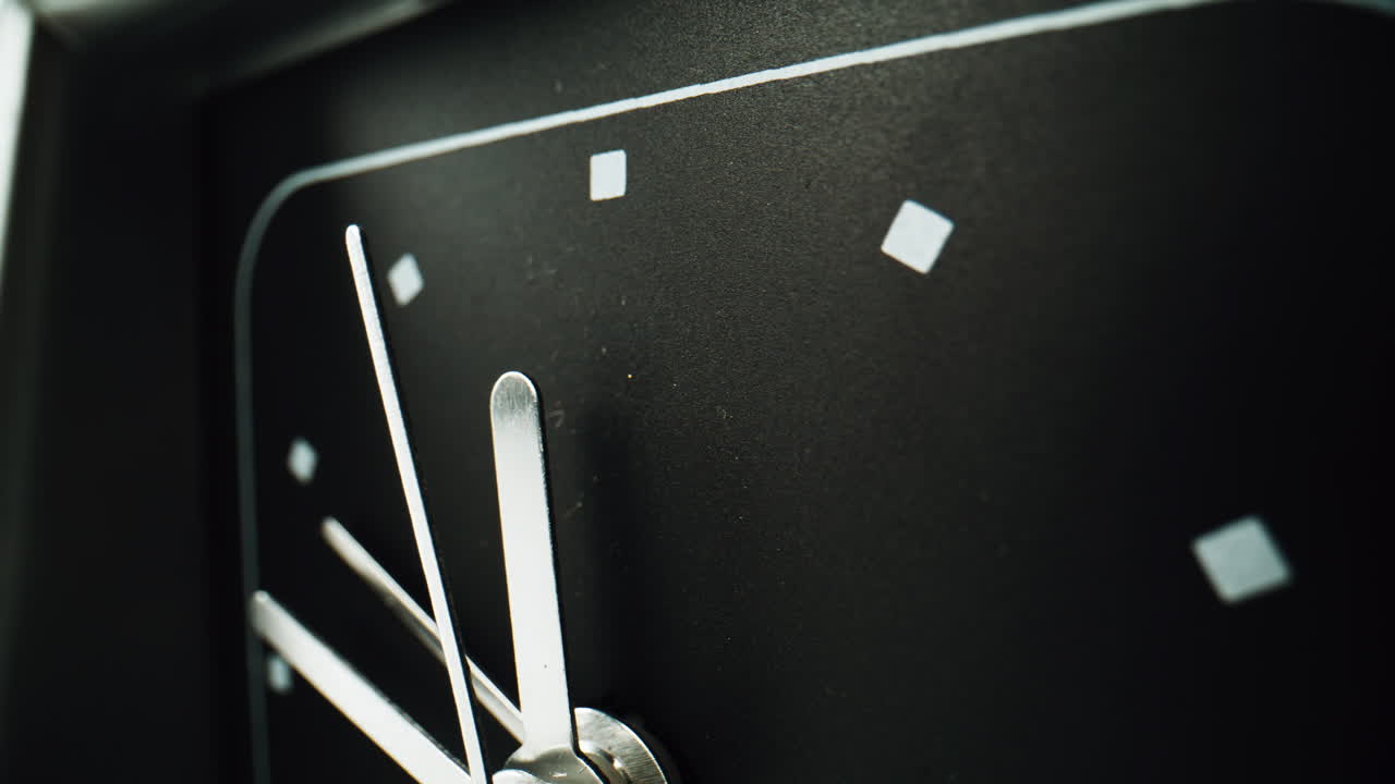 Closeup arrows ticking black clock background. Macro view metal hand running
