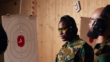 portrait of happy army soldiers in shooting gallery comparing targets shot